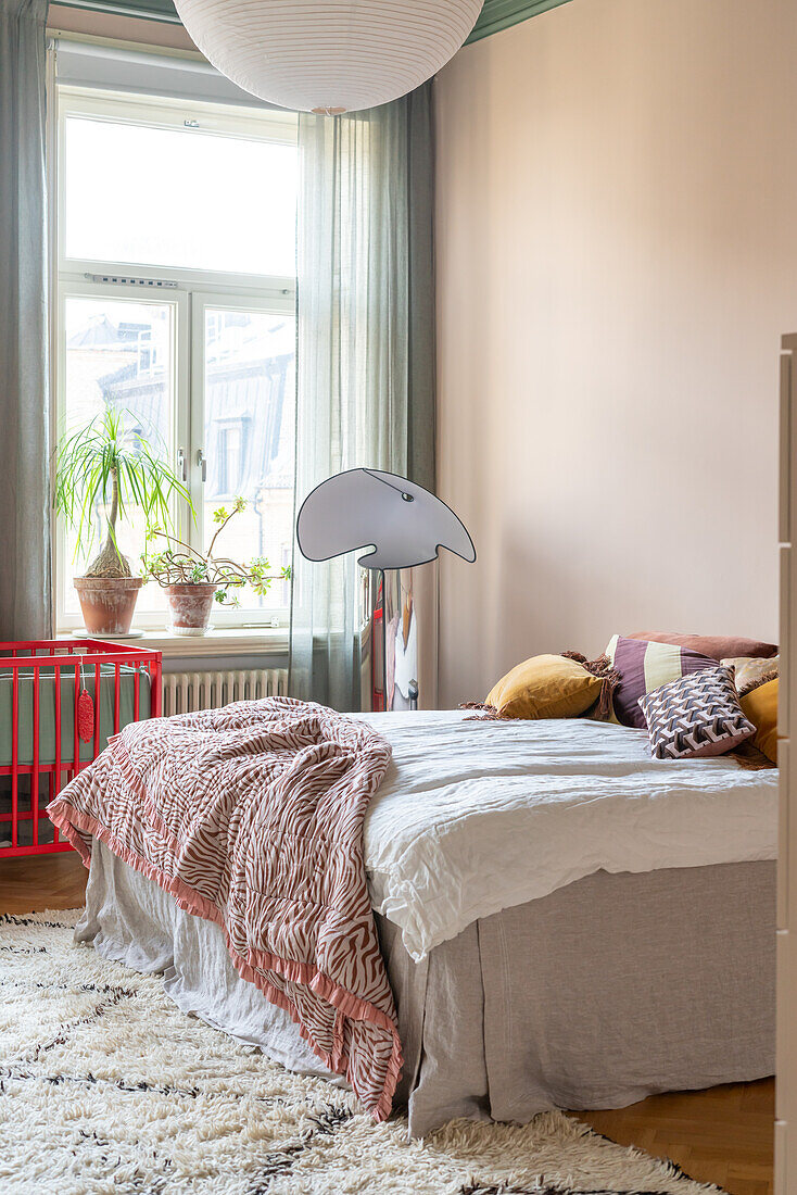 Schlafzimmer mit Bett, flauschigem Teppich und Pflanzen auf der Fensterbank