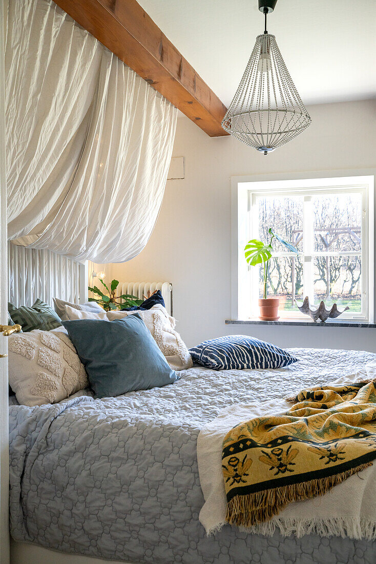 Bed with canopy and hanging lamp in bedroom