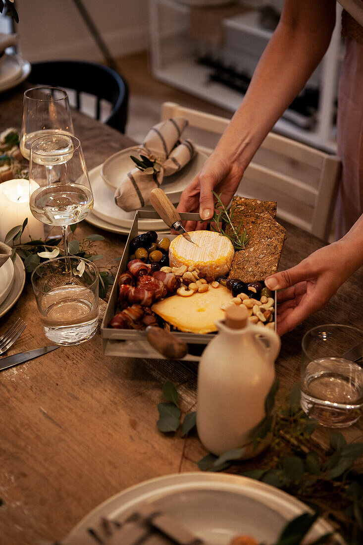 Table set with cheese, dates wrapped in bacon, olives and wine glasses for a dinner party