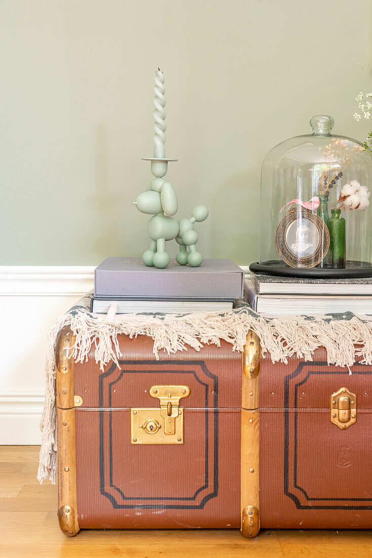 Vintage suitcase as side table with decorative glass bell jar and candle