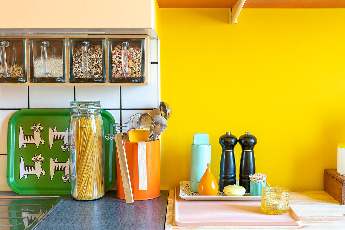 Vorratsbehälter und Küchenutensilien vor gelber Wand