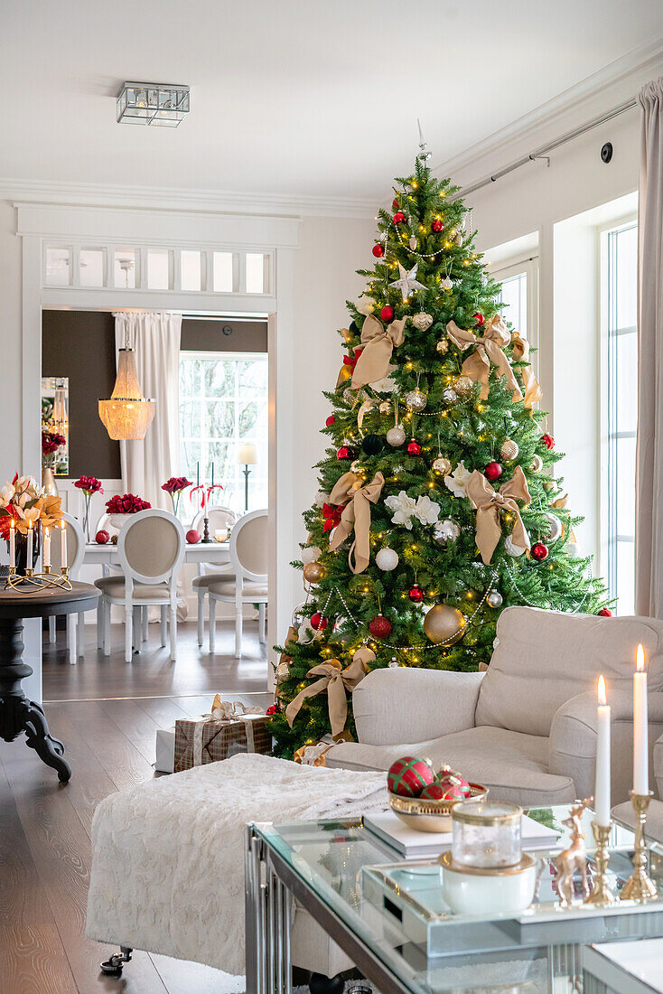 Weihnachtlich geschmückter Wohnbereich mit großem Tannenbaum und Kerzen