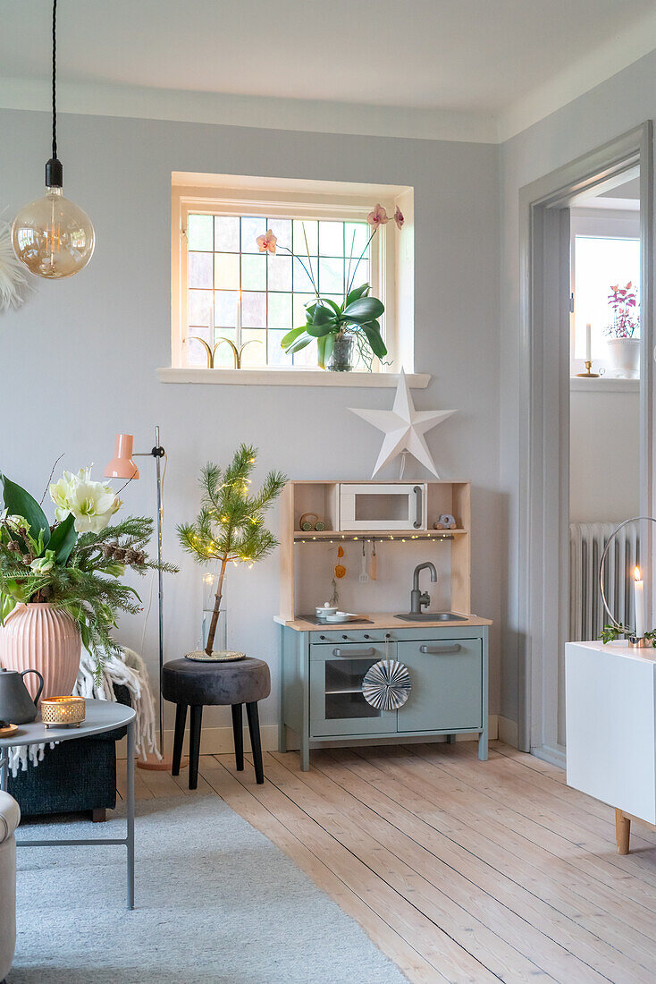 Children's play kitchen in pastel blue with Christmas decorations in the living room