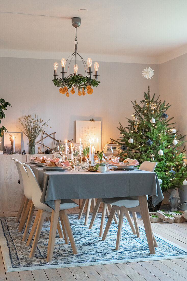 Festlich gedeckter Esstisch mit Weihnachtsbaum und Kronleuchter