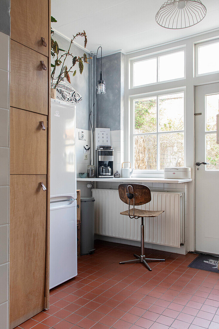 Kitchen with wooden cupboard, floor tiles and retro wooden chair by the window