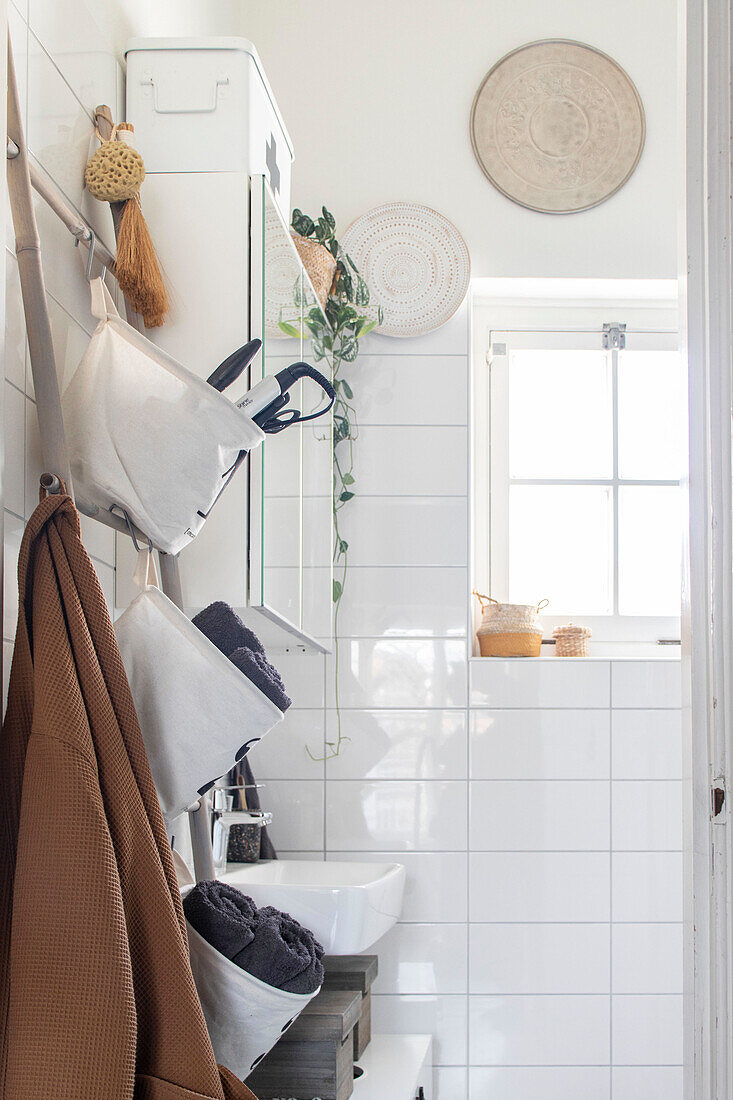 Bright bathroom with white tiles, hanging baskets and plant