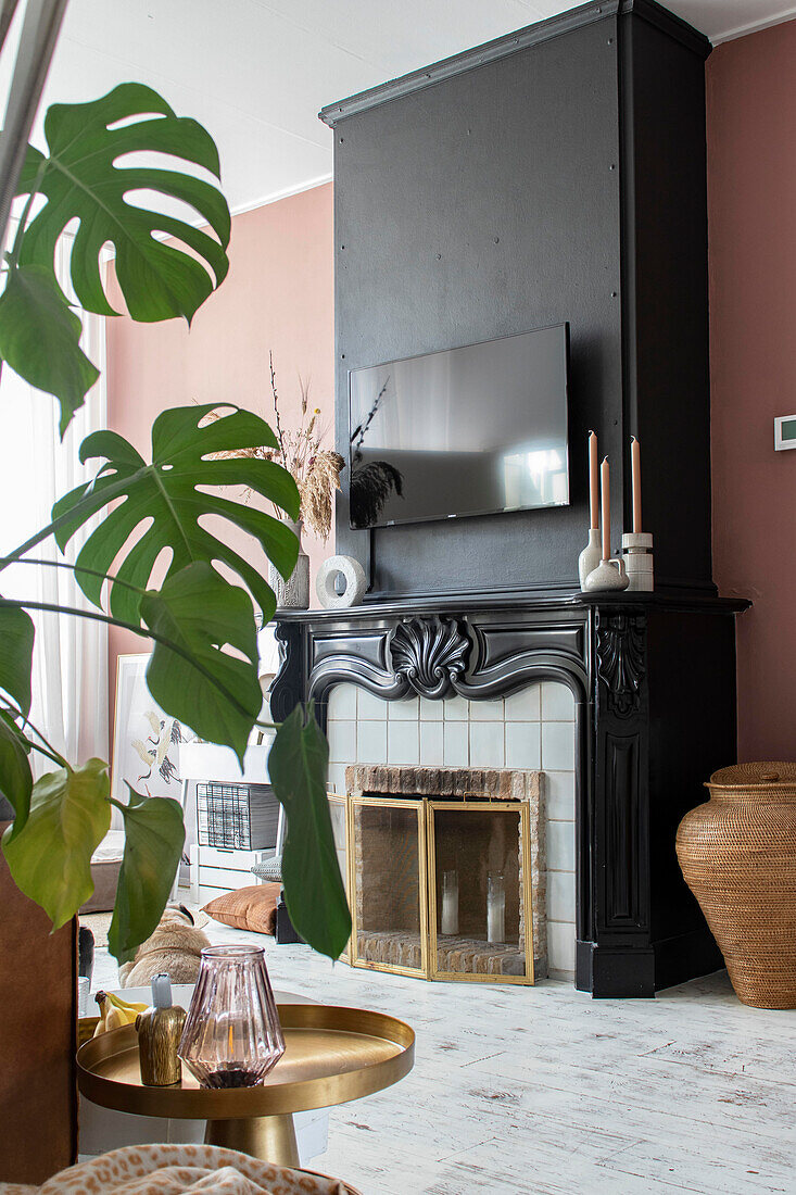 Living room with fireplace, monstera plant and golden side table