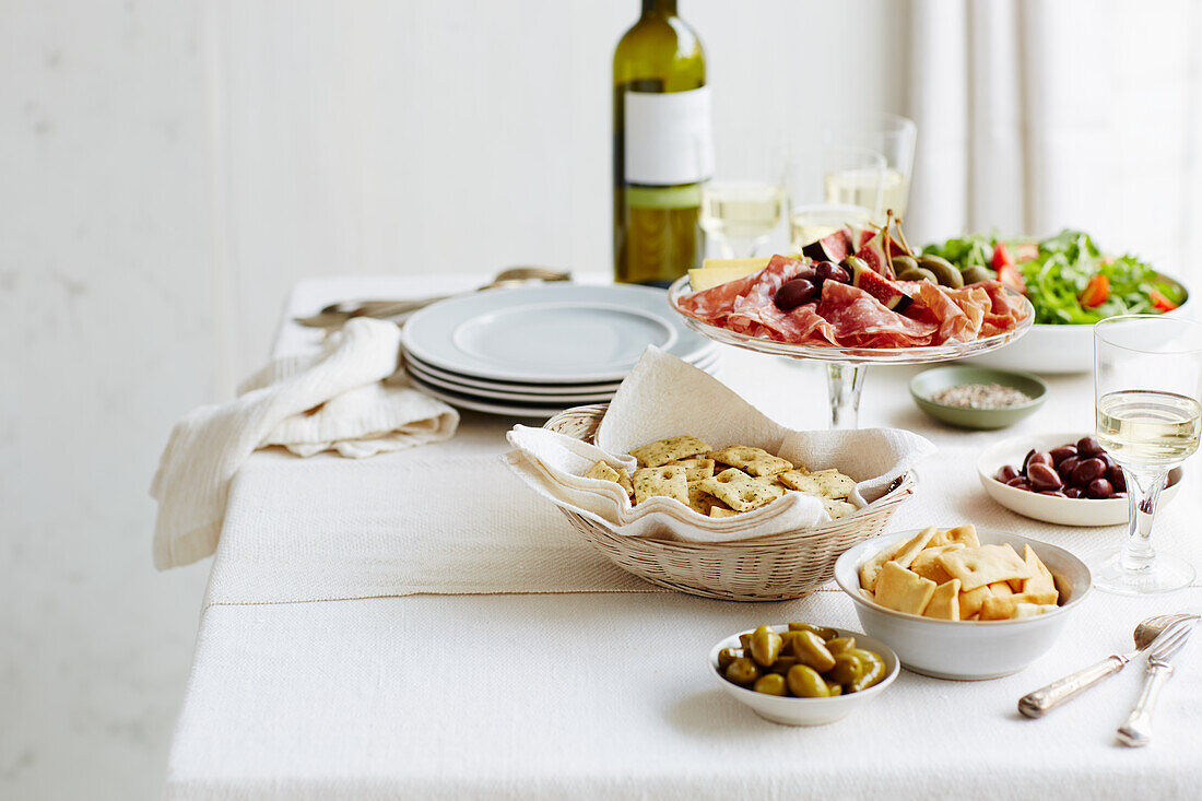 Aufschnittsplatte, Oliven, Salat, Cracker und Wein
