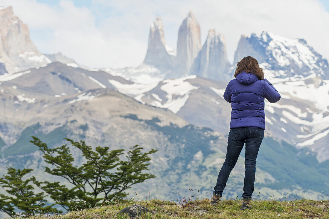 A Woman Stands With A View Of The Rugged Mountain Landscape, Torres Del Paine National Park; Torres Del Paine, Magallanes And Antartica Chilena Region, Chile