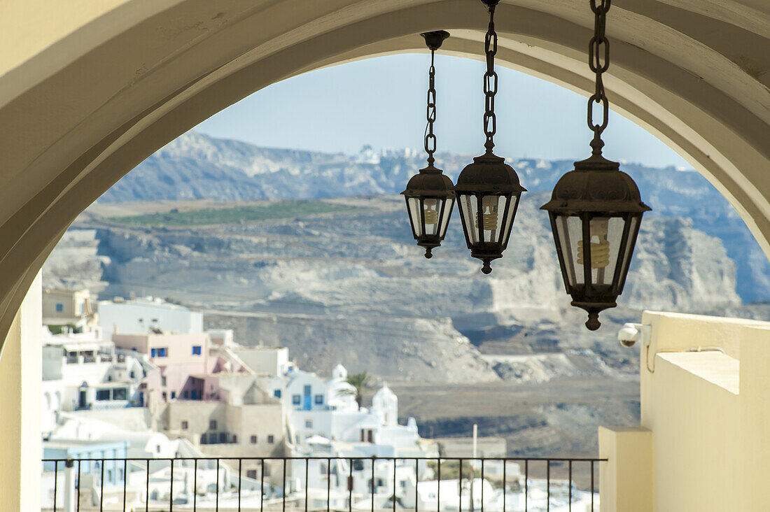 Lights Hang From An Arched Ceiling With A View Of A Church, Whitewashed Buildings And Landscape; Fira, Santorini, Greece