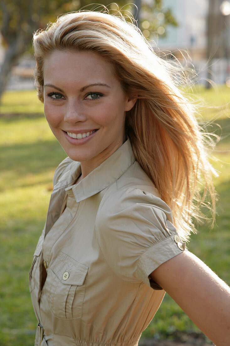 Blonde Frau in hellem Blusenkleid im Freien