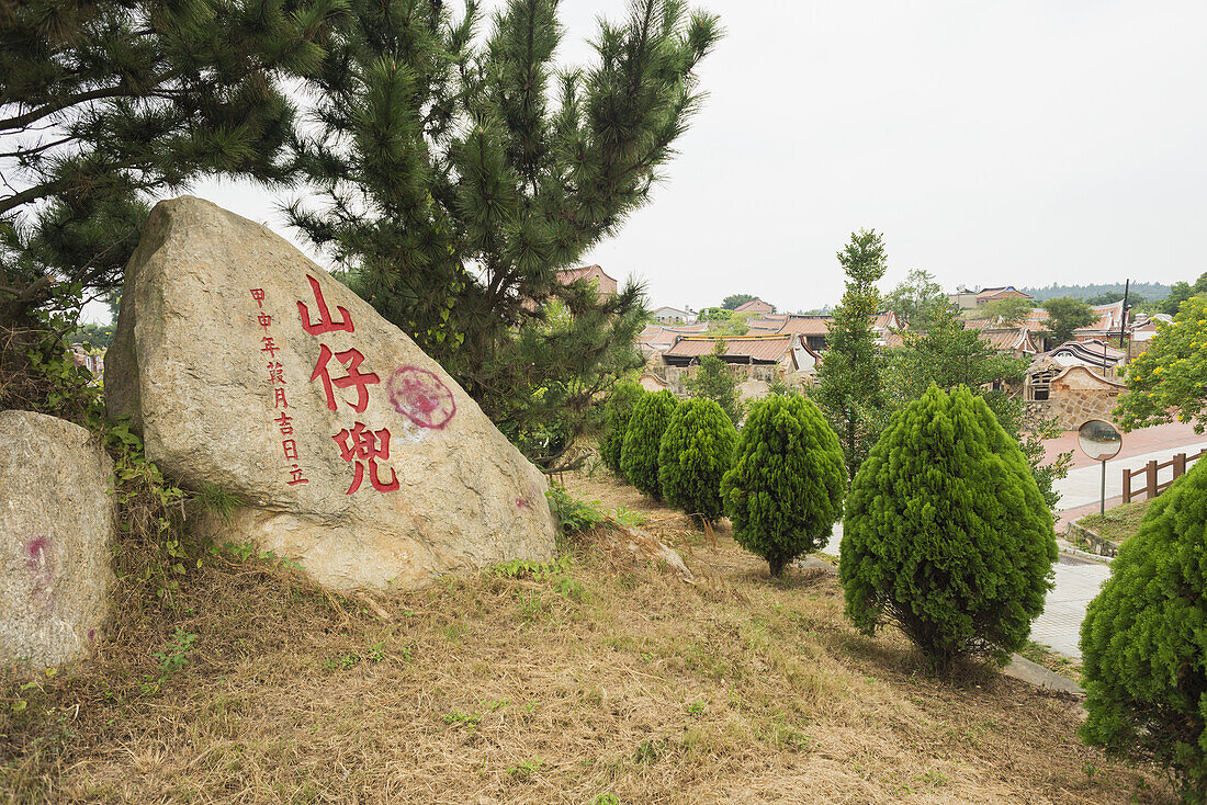Rote chinesische Schriftzeichen auf einem Felsen in einem traditionellen Dorf; Shanzidou, Kinmen, Taiwan