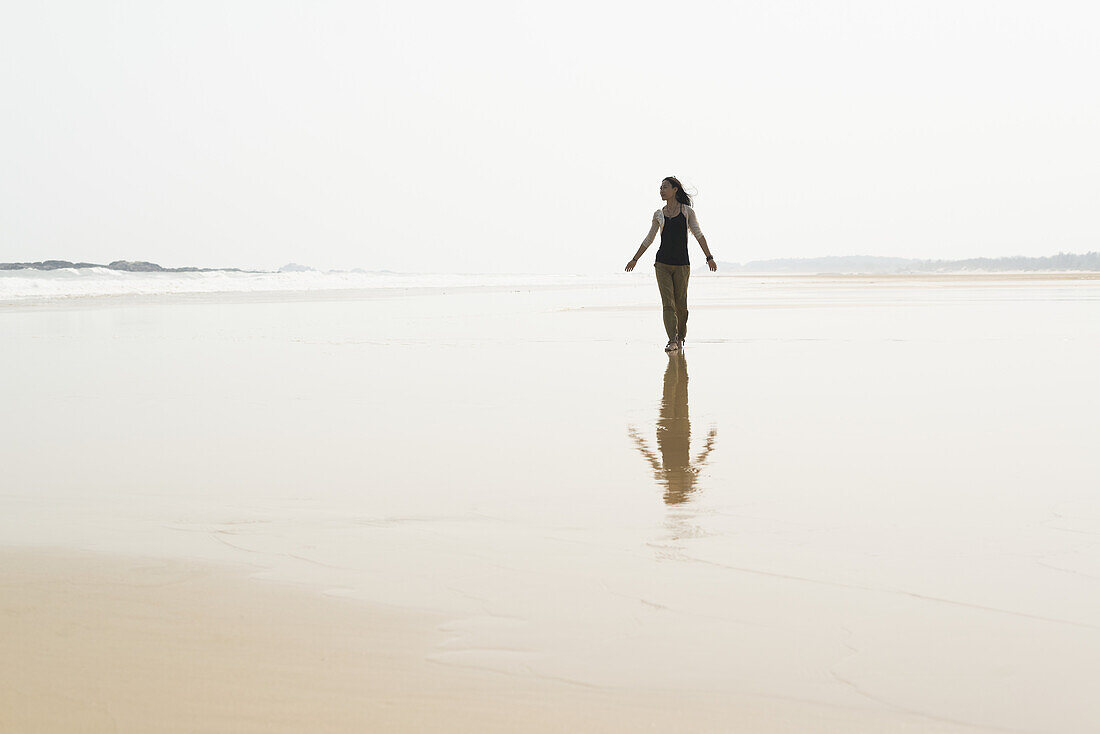 Junge Frau, die am Strand von Huohu, im Norden der Insel Kinmen, spazieren geht; Taiwan