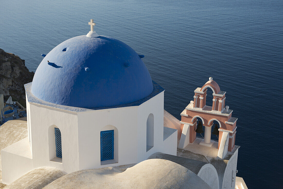 Eine blaue Kuppelkirche und ein rosafarbener Glockenturm mit Blick auf die Caldera; Oia, Santorin, Kykladen, Griechische Inseln, Griechenland