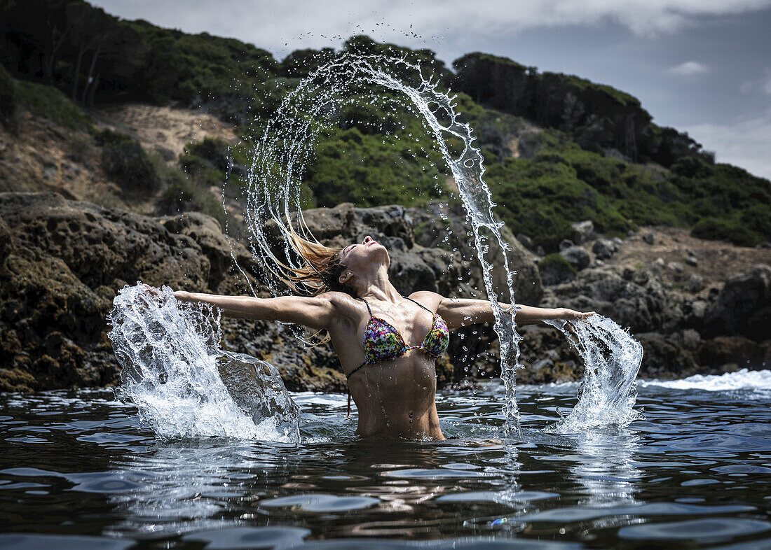 A Young Woman In A Bikini Splashing Water Along The Water's Edge; Tarifa, Cadiz, Andalusia, Spain
