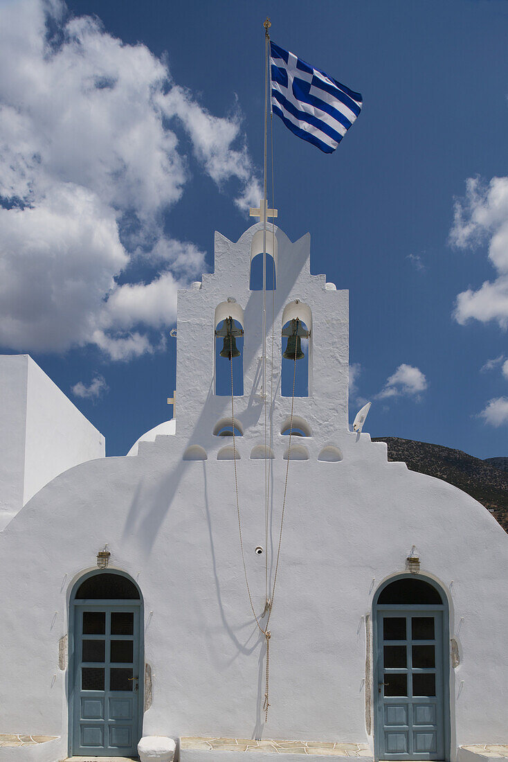 Eine griechische Flagge weht über einer weiß gewaschenen Kirche; Vathi, Sifnos, Kykladen, Griechische Inseln, Griechenland