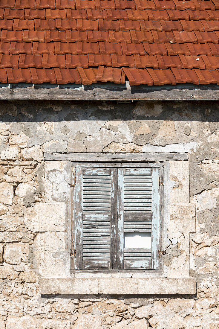 Broken And Weathered Shutters On A Window Of A Stone Building With Ceramic Tile Roof; Paphos, Cyprus