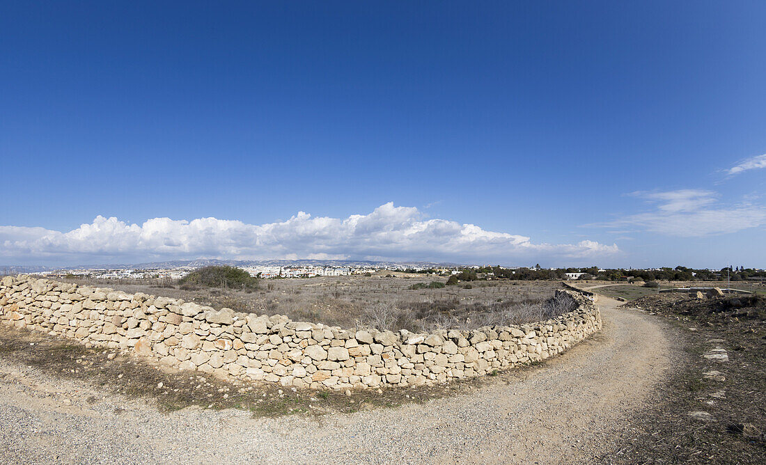 Eine Kurve in einer Schotterstraße und Steinmauer; Paphos, Zypern