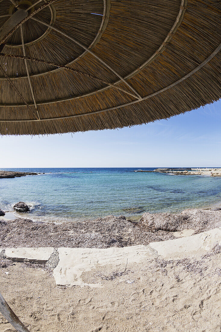 View Of The Mediterranean From Under A Thatched Umbrella At The Water's Edge; Paphos, Cyrpus