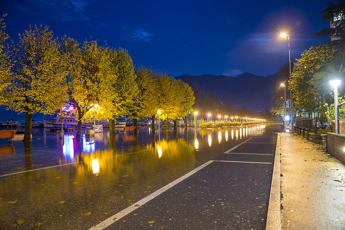 Reflexion von Lichtern und Bäumen im Wasser aufgrund der Überflutung des Lago Maggiore; Locarno, Tessin, Schweiz