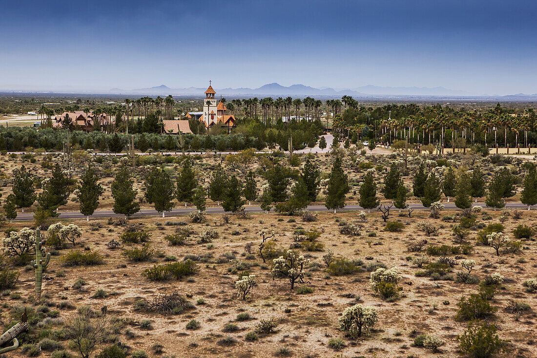 Kirchturm mit Kreuz und Bäumen und Pflanzen in karger Landschaft; Phoenix, Arizona, Vereinigte Staaten von Amerika