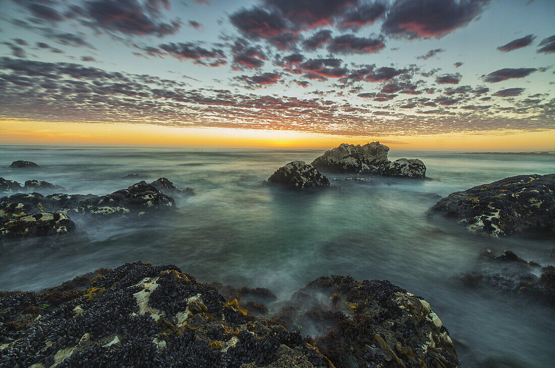 Rote Wolken bei Sonnenuntergang über dem Meer entlang der Küste Südafrikas in der Nähe der Hondeklip Bay; Namakwa, Südafrika
