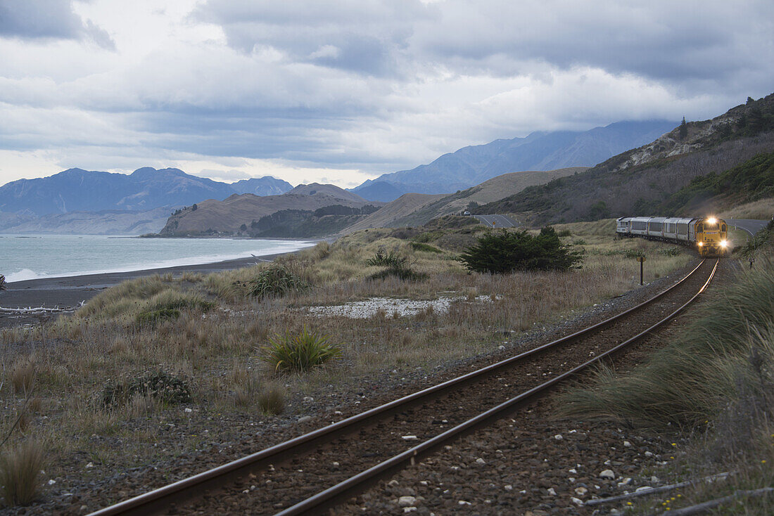 Annähernder Zug mit malerischer See- und Bergkulisse an der Ostküste von Neuseelands Südinsel; Neuseeland
