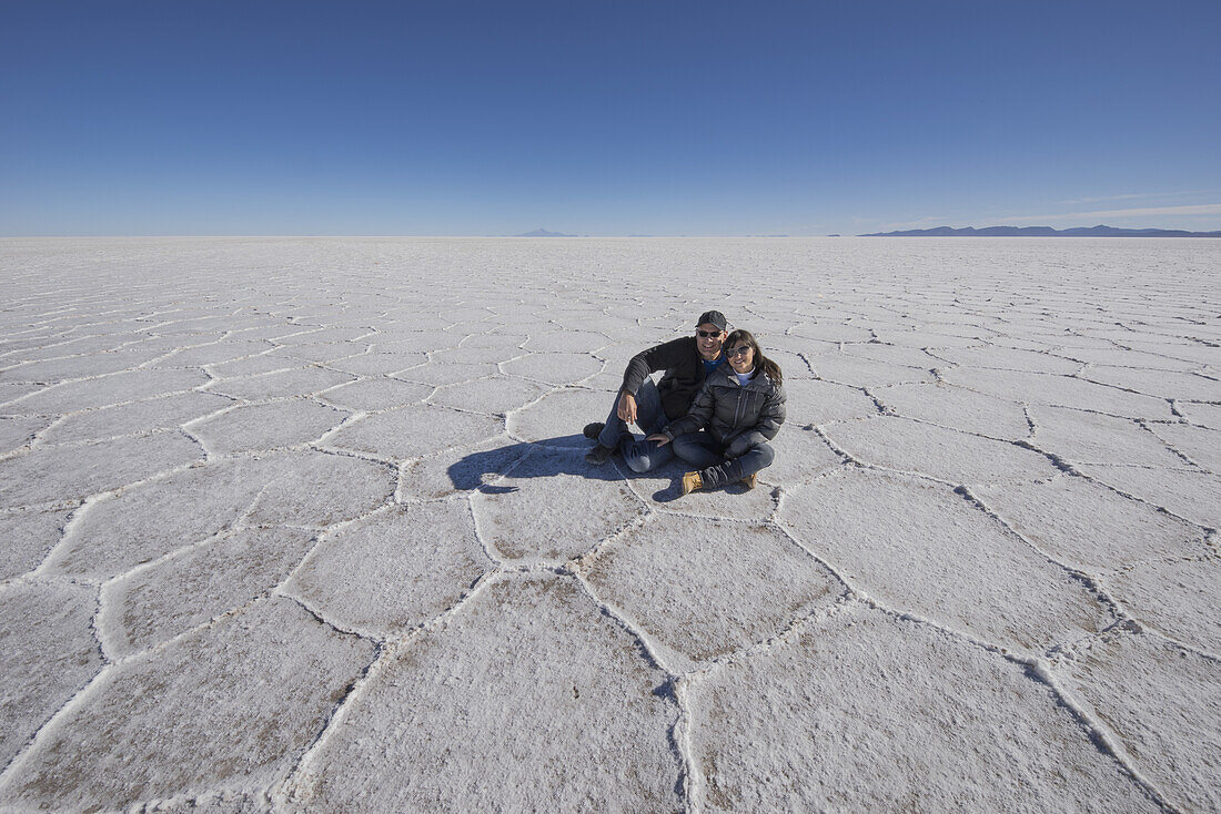 Ein Paar sitzt auf den Salzebenen des Salar De Uyuni; Bolivien