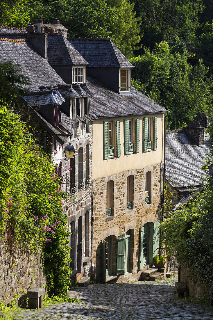 Alte Steingebäude mit grünen Fensterläden an einer Kopfsteinpflasterstraße; Dinan, Bretagne, Frankreich