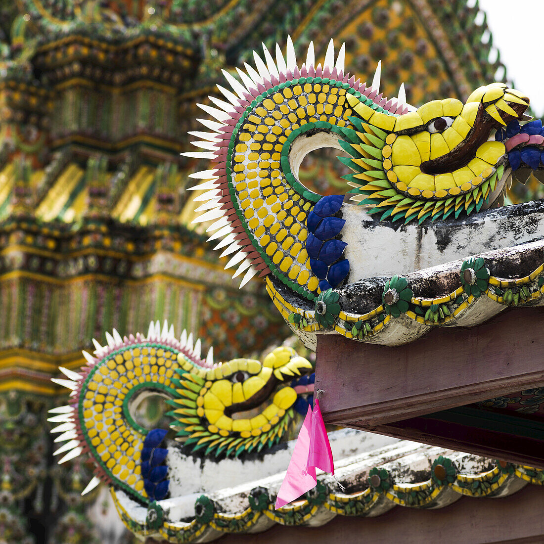 Bunte Skulptur eines Drachens mit einem verzierten Gebäude im Hintergrund; Bangkok, Thailand