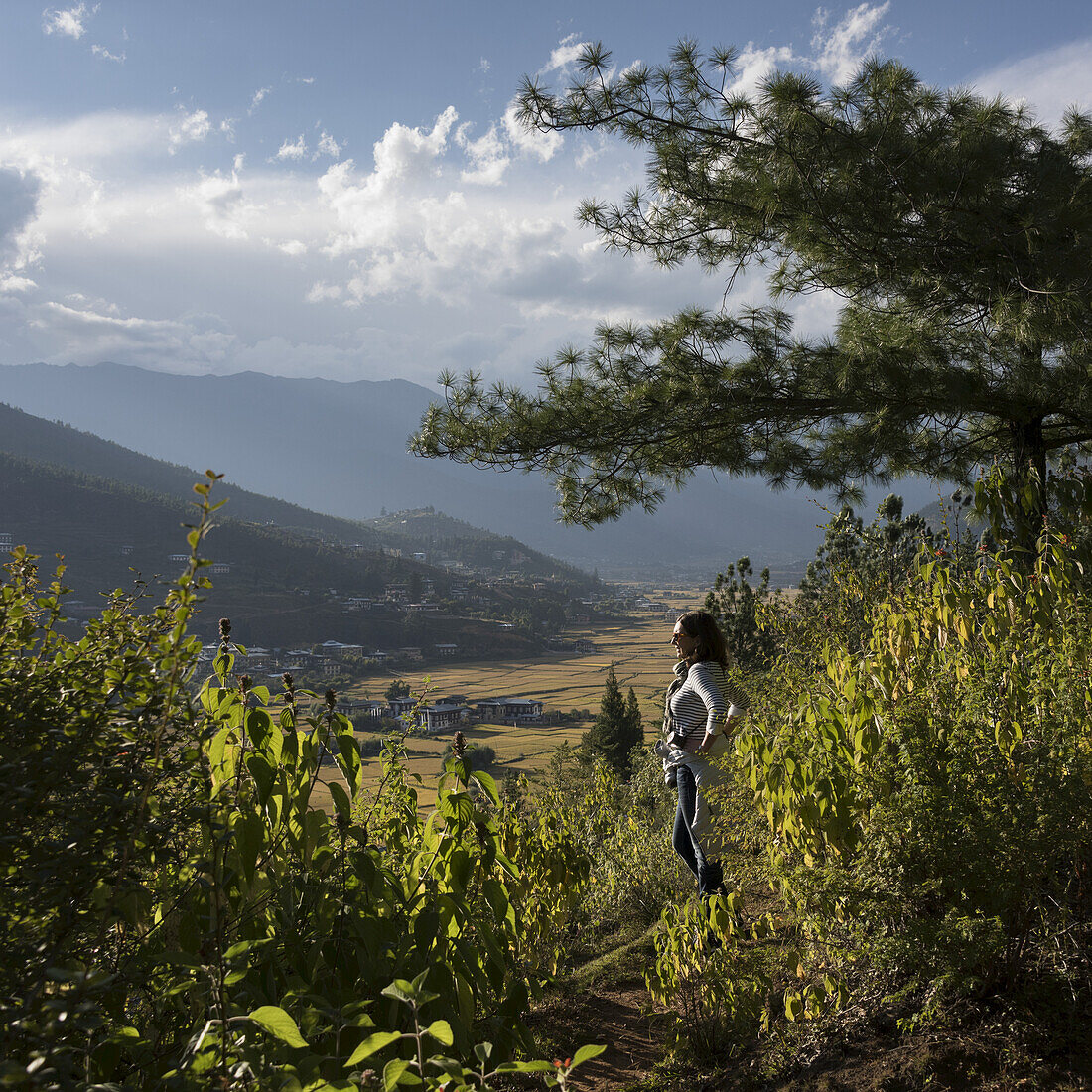 Eine Frau steht und schaut über das Paro-Tal; Paro, Bhutan