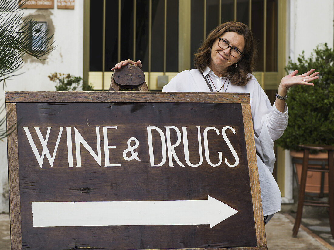 A Woman Posing With A Sign For Wine And Drugs; Ravello, Italy