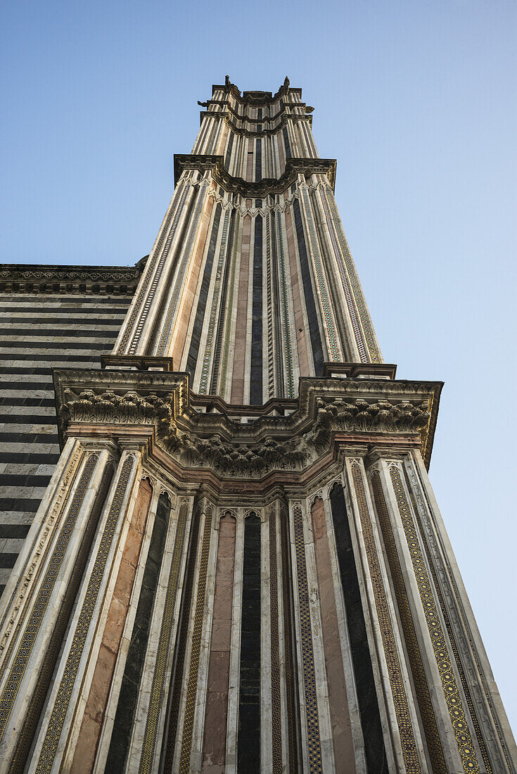 Niedriger Blickwinkel auf eine gestreifte Fassade eines Turms der Kathedrale von Orvieto; Orvieto, Umbrien, Italien