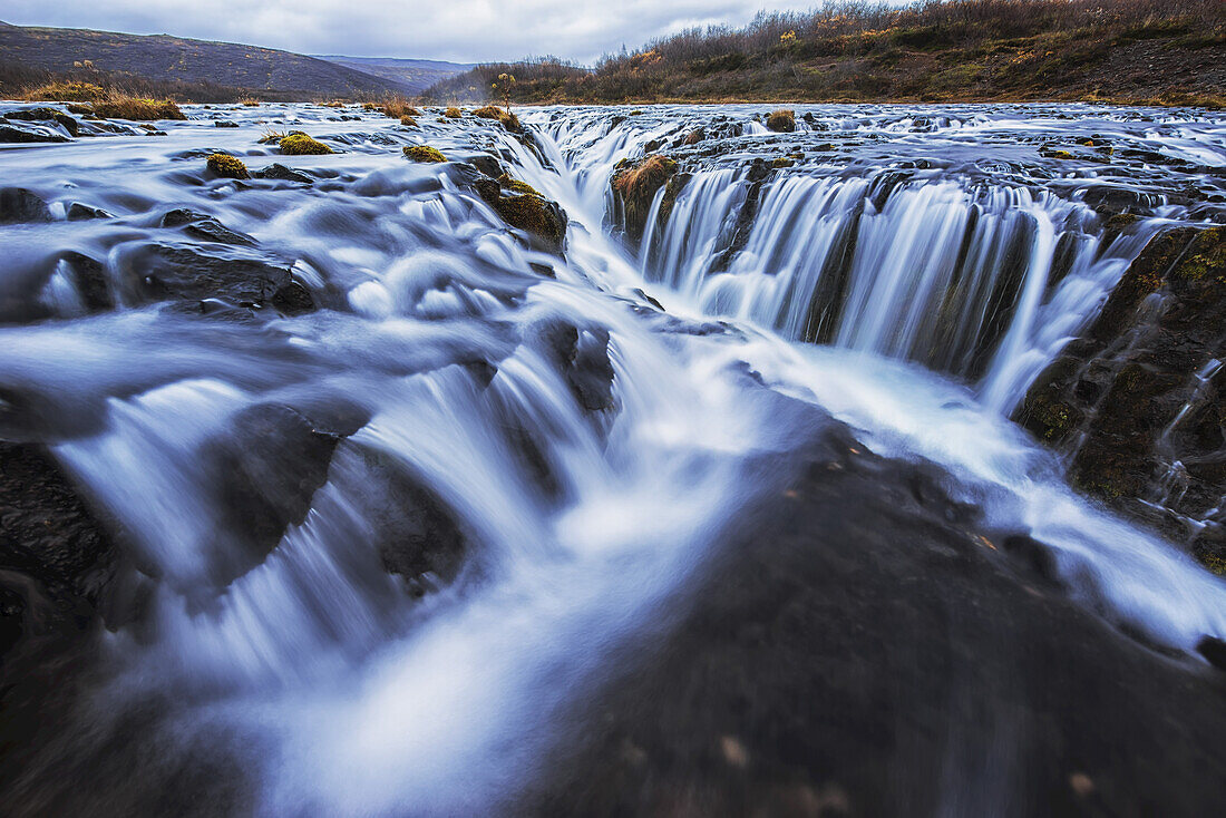 Water Cascading Over Rock On A Landscape With Autumn Colored Foliage; Bruarfoss, Iceland