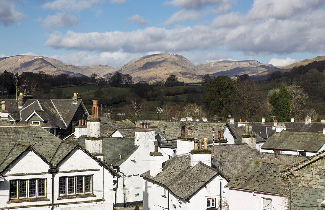 White Houses And Rooftops With Mountains In The Distance; Hawkshead, England