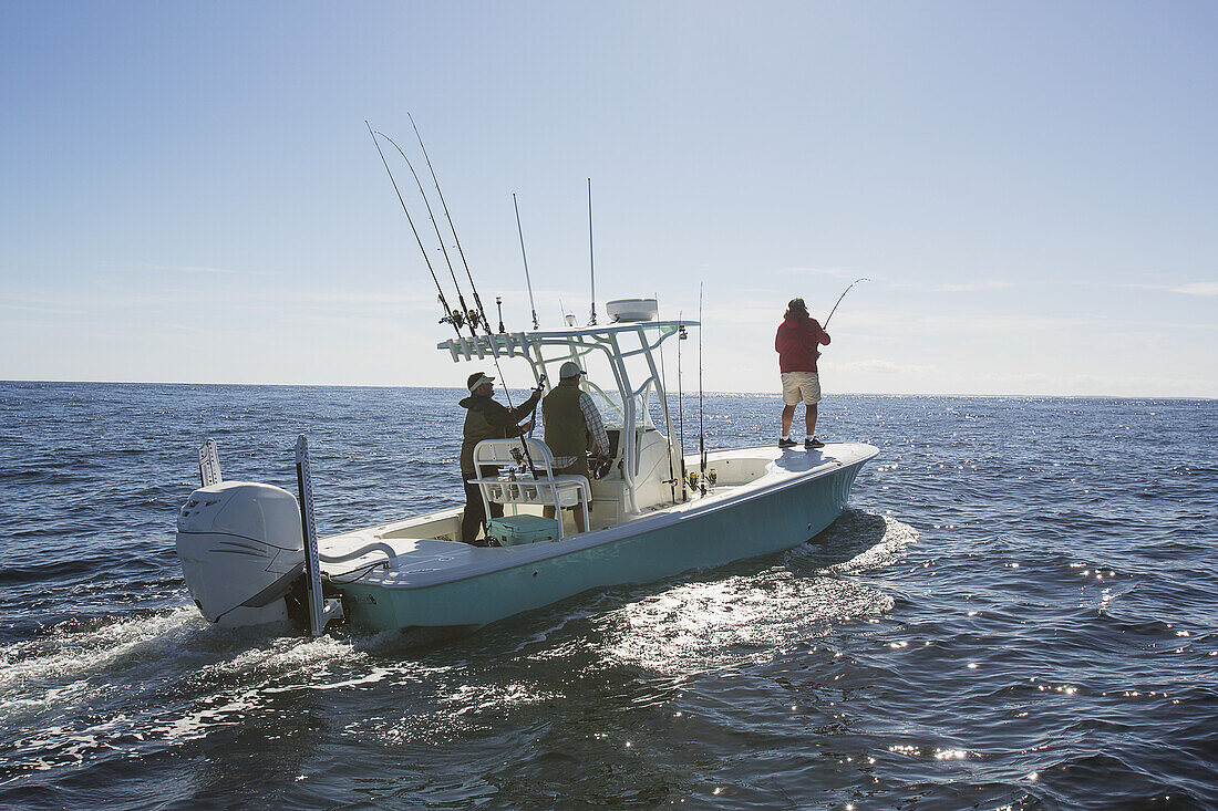 A Man Standing Fishing Off The Edge Of A Boat On The Atlantic Coast; Cape Cod, Massachusetts, United States Of America