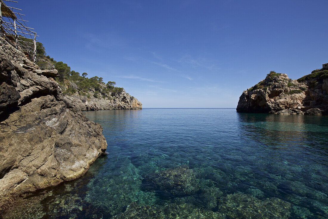 Kristallklares Wasser und Strandcafé auf einem felsigen Vorsprung, Bucht von Deia, Mallorca