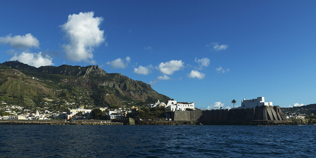 Ischia Island With Walls Along The Waterfront And White Buildings Up On The Promontory; Ischia, Italy