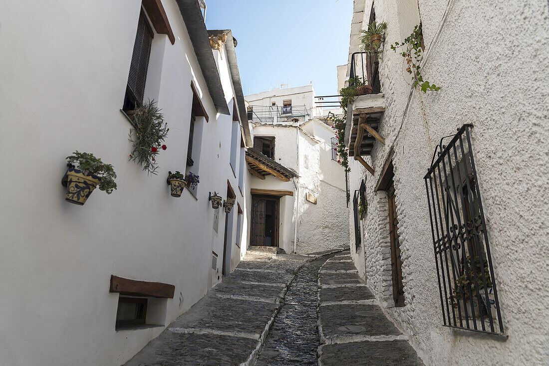 Eine abschüssige Straße zwischen Häusern in Pampaneira, einem der bekanntesten Dörfer in der Alpujarra; Provinz Granada, Andalusien, Spanien