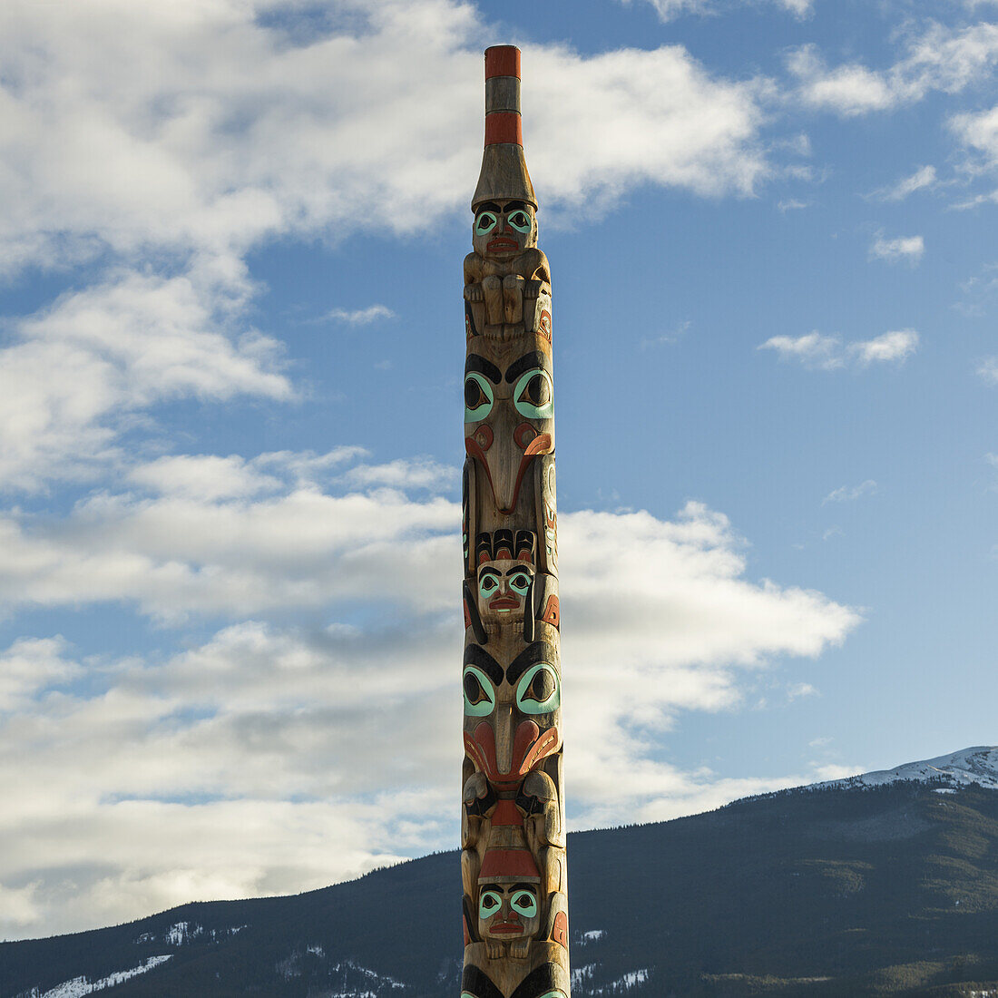 Totem Pole Against A Blue Sky With Cloud And A Mountain In The Background, Jasper National Park; Alberta, Canada