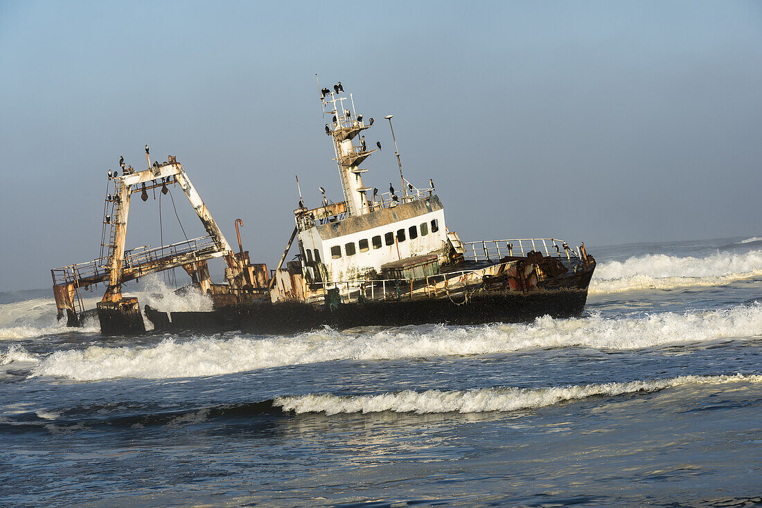 Ein rostiges, gesunkenes, verlassenes Schiff in den Wellen des Atlantiks an der namibischen Küste (Zeila Schiffswrack); Namibia