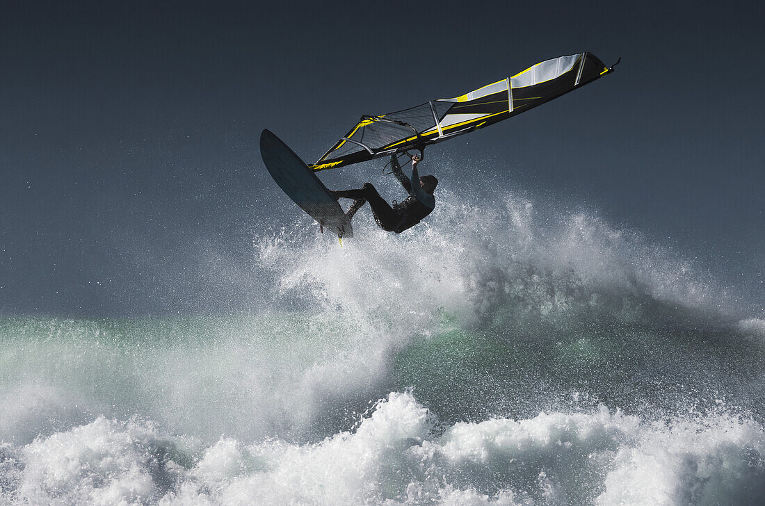 Windsurfer in der Luft über plätschernden Wellen; Tarifa, Cadiz, Andalusien, Spanien