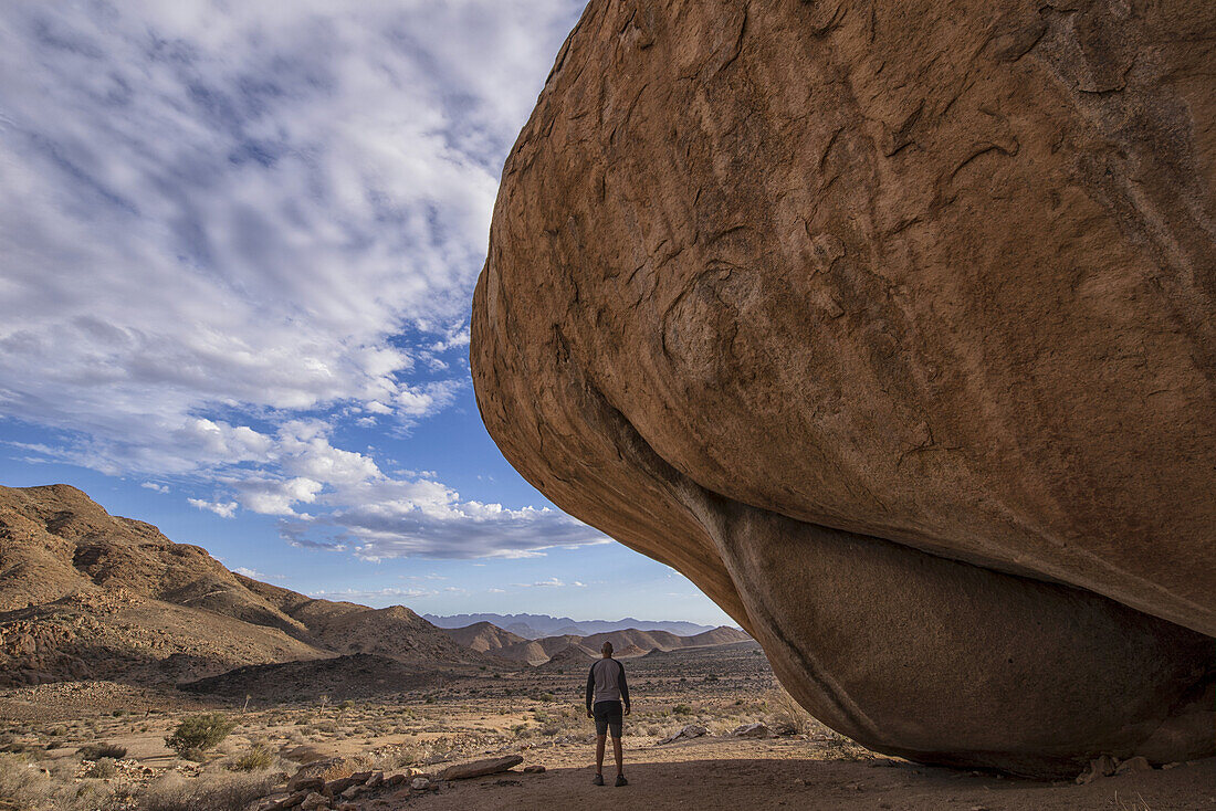 Mann steht unter einem riesigen Felsbrocken im Richtersveld National Park; Südafrika