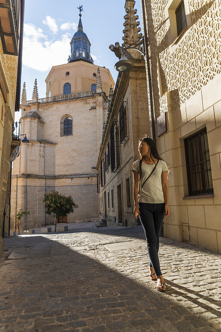 Asian Girl Walking Along The Street With Segovia's Cathedral As Background; Castilla Leon, Spain