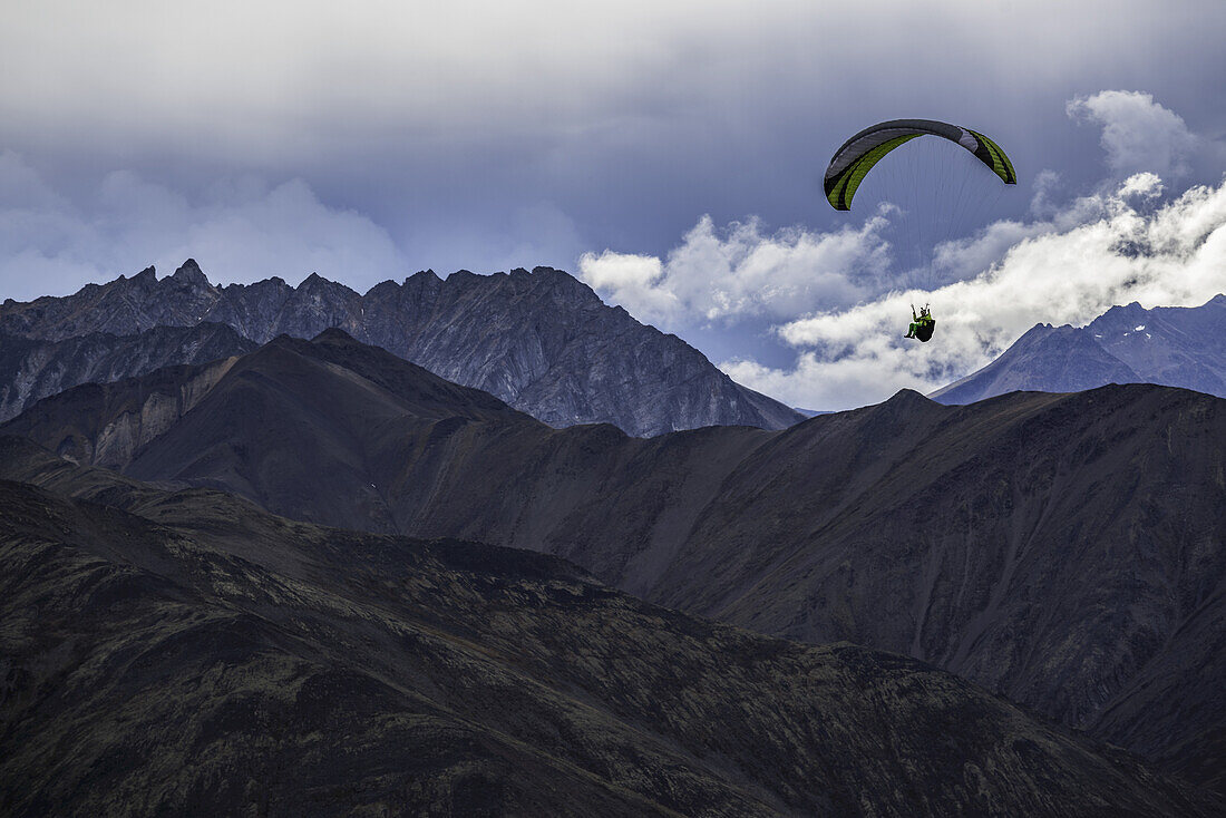 Man Paragliding Over The Mountain Of The Tombstone Range Along The Dempster Highway; Yukon, Canada