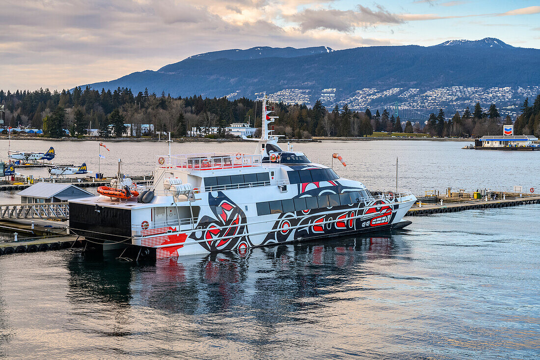 Ferry with indigenous artwork painted on the side, moored at a waterfront; Vancouver, BC, Canada