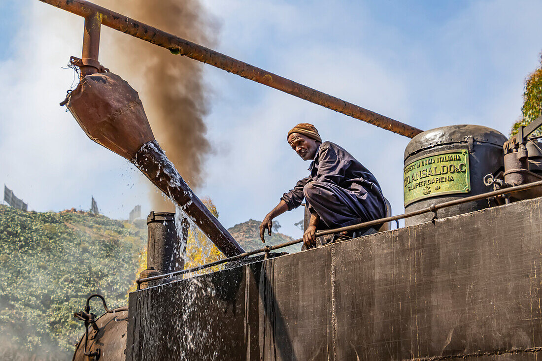 Engineer adding water to the Ansaldo 442 steam locomotive built in 1938, used for transporting cargo from the port city of Massawa to the capital Asmara; Arbaroba, Central Province, Eritrea