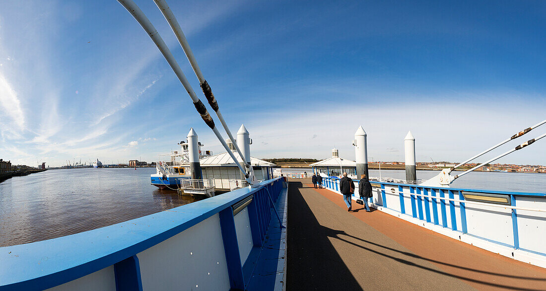 Menschen gehen den Pier hinunter in Richtung einer Fähre auf dem Fluss Tyne; South Shields, Tyne and Wear, England