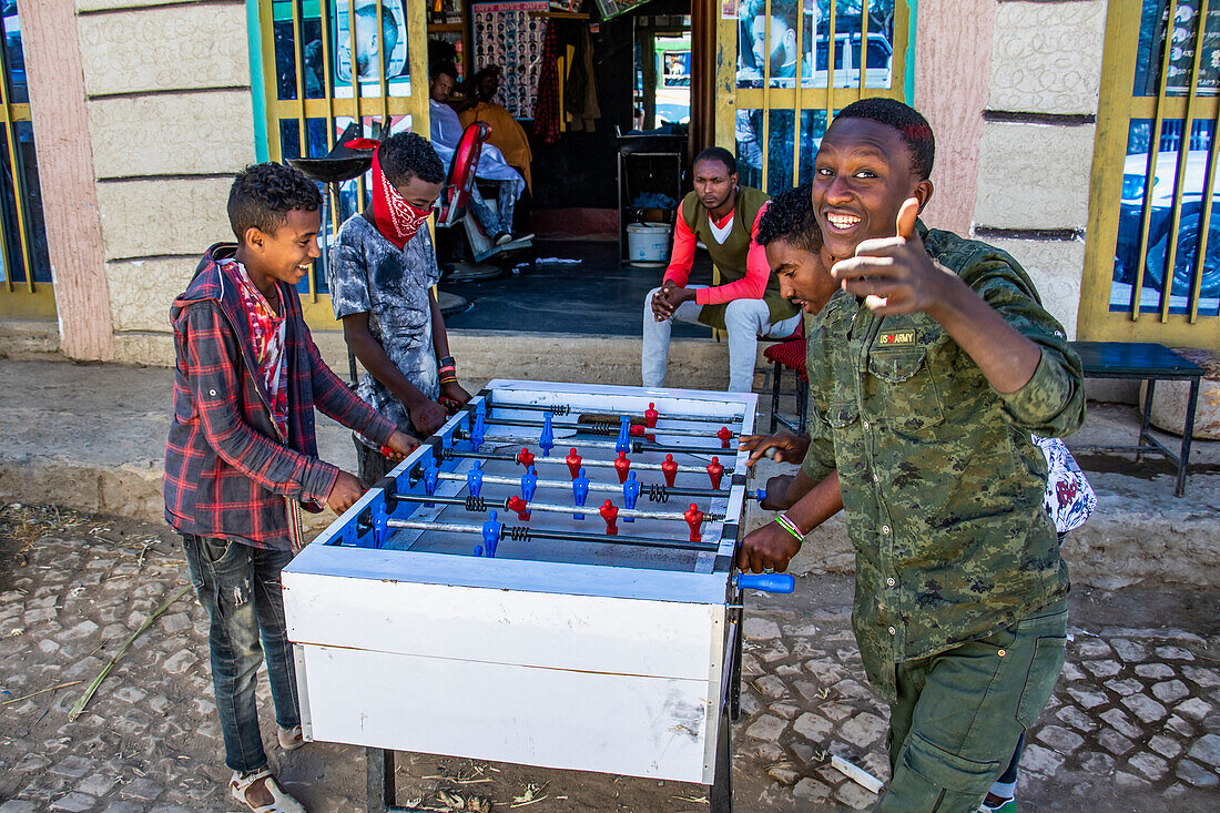 Äthiopische Jungen spielen Tischfußball auf der Straße vor einem Friseursalon; Agula, Region Tigray, Äthiopien