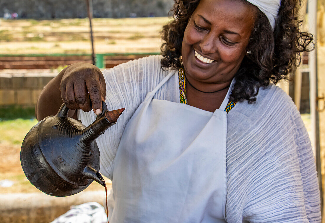 Woman serving coffee in jebena buna, a traditional Ethiopian coffee ceremony; Addis Ababa, Addis Ababa, Ethiopia